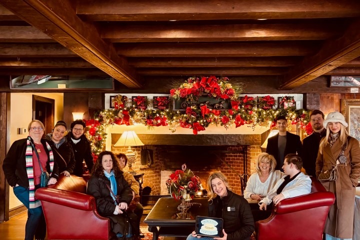 A group of people in a festive room with holiday decorations and a fireplace.