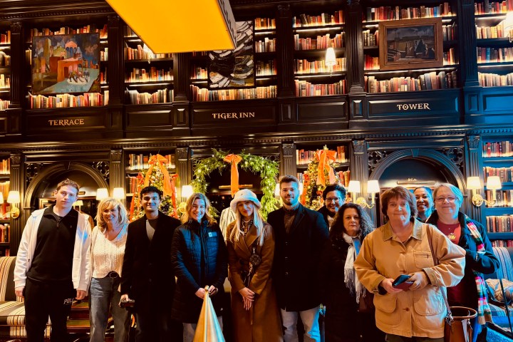 Group of people standing in a library with festive decorations.